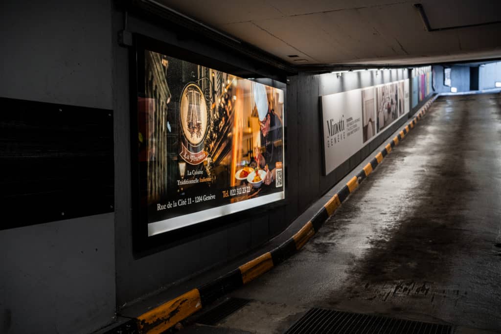 Campagne publicitaire rétroéclairée installée le long des rampes du parking du Mont-Blanc à Genève, avec des affiches aux formats F12, F4 et A0L offrant une visibilité continue sur plusieurs niveaux.