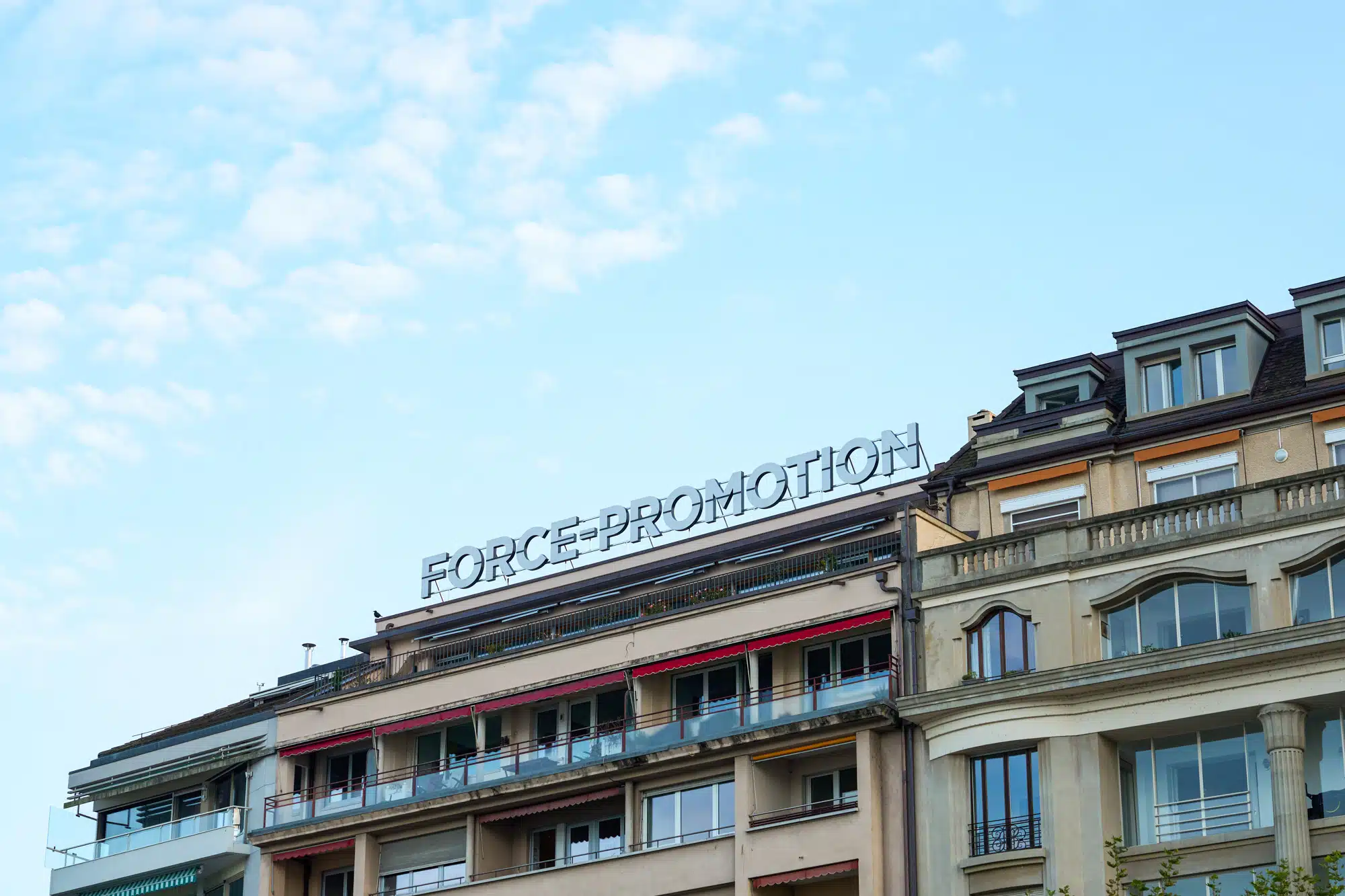 Enseigne lumineuse de Force Promotion installée sur un toit en centre-ville de Genève, emblème de visibilité urbaine haut de gamme