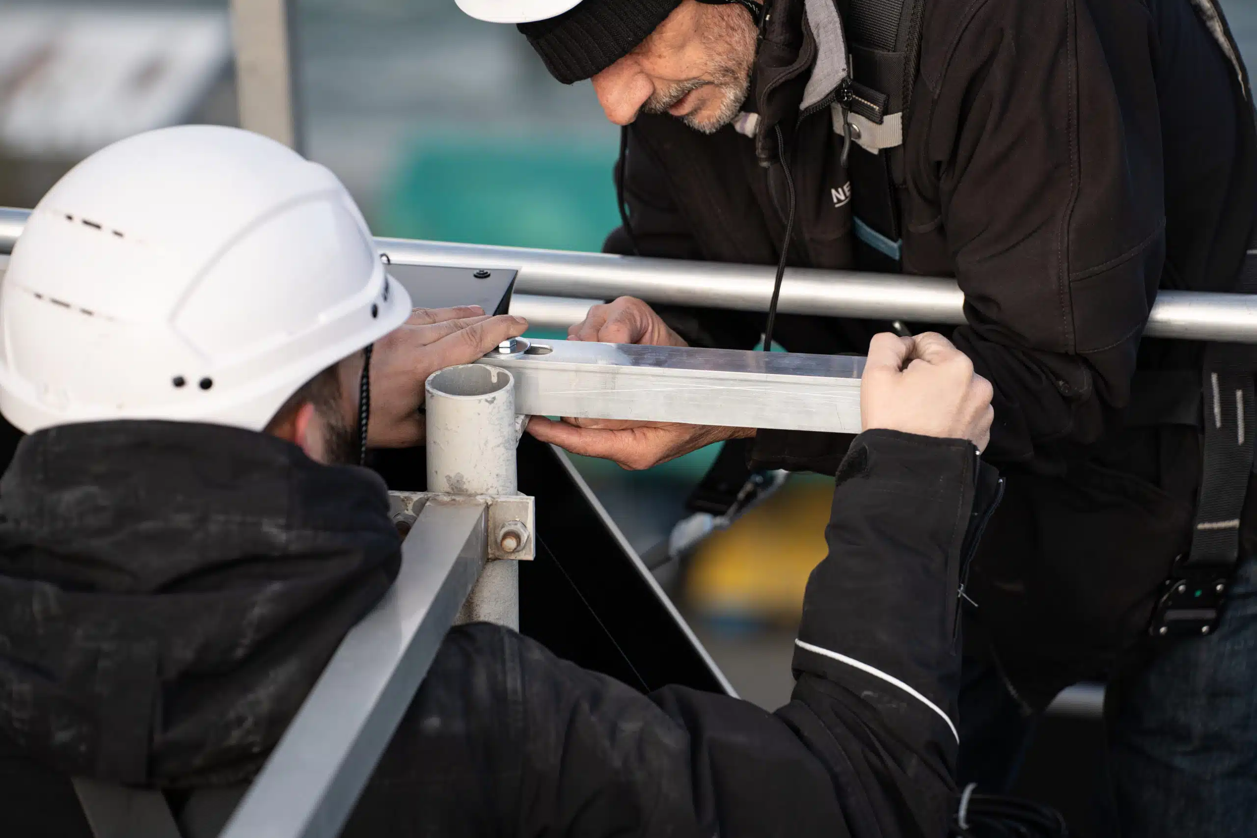 Deux techniciens posent une enseigne lumineuse connectée sur le toit d'un immeuble de la rade de Genève, en assurant un montage précis et sécurisé