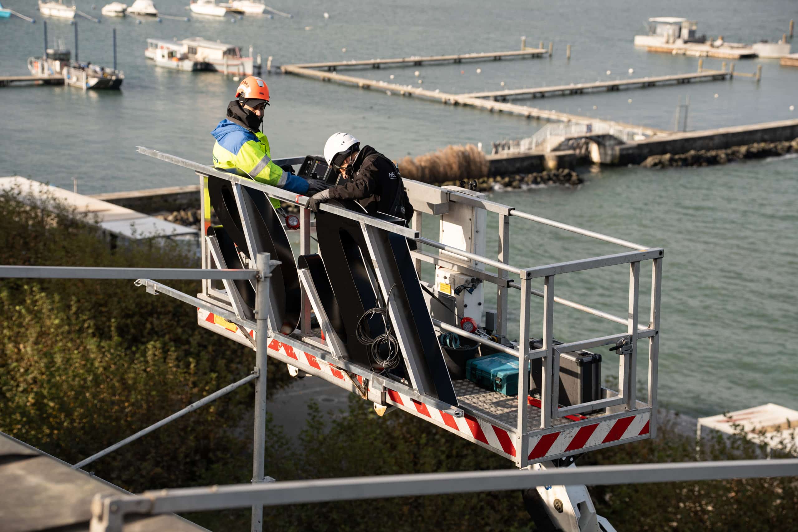 Workers installing an illuminated sign on a roof in Geneva, using safety equipment