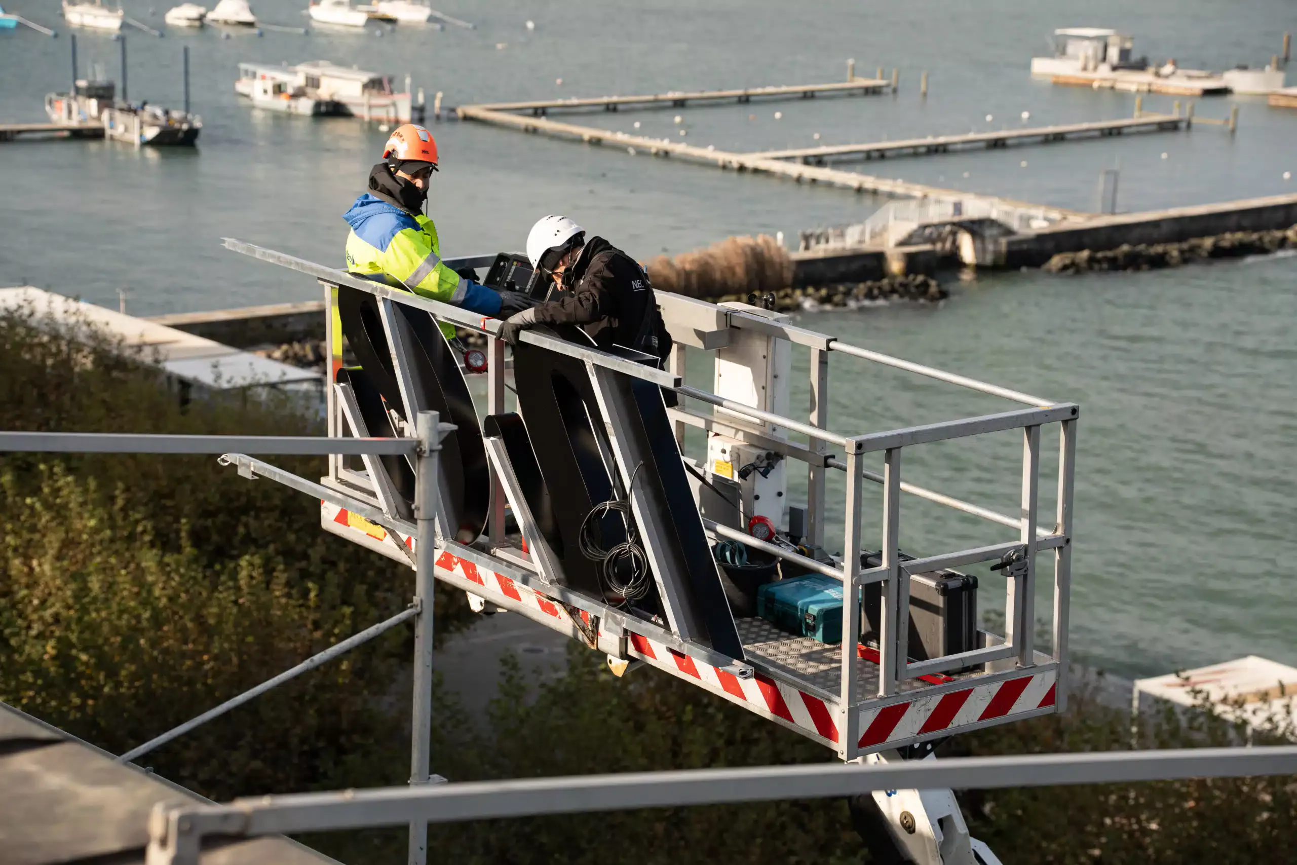 Ouvriers installant une enseigne lumineuse sur un toit à Genève, avec des équipements de sécurité