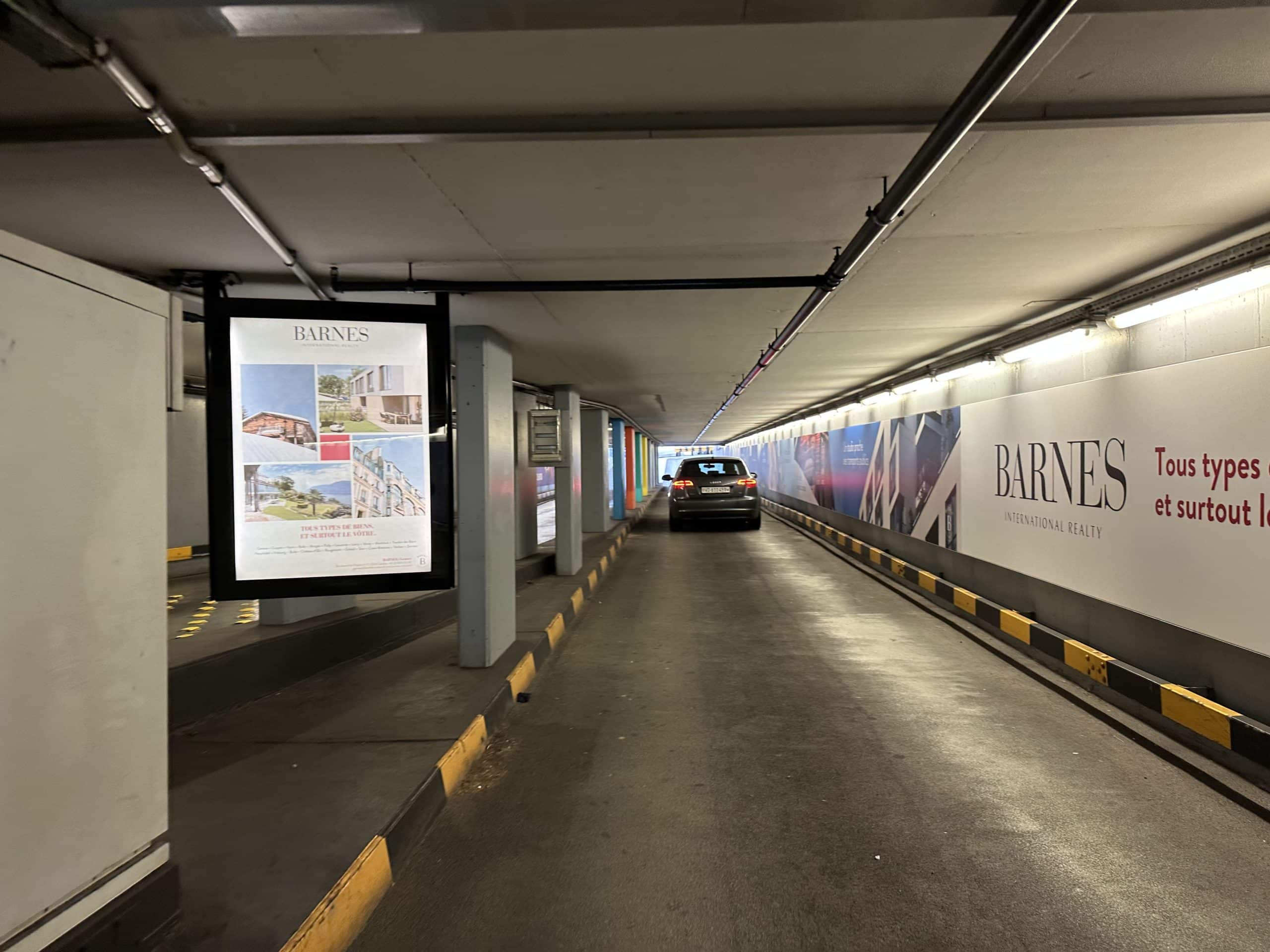 Affichage A0L rétro-éclairé recto-verso BARNES au parking du Mont-Blanc à Genève, mettant en valeur des biens immobiliers de prestige à vendre ou à louer.