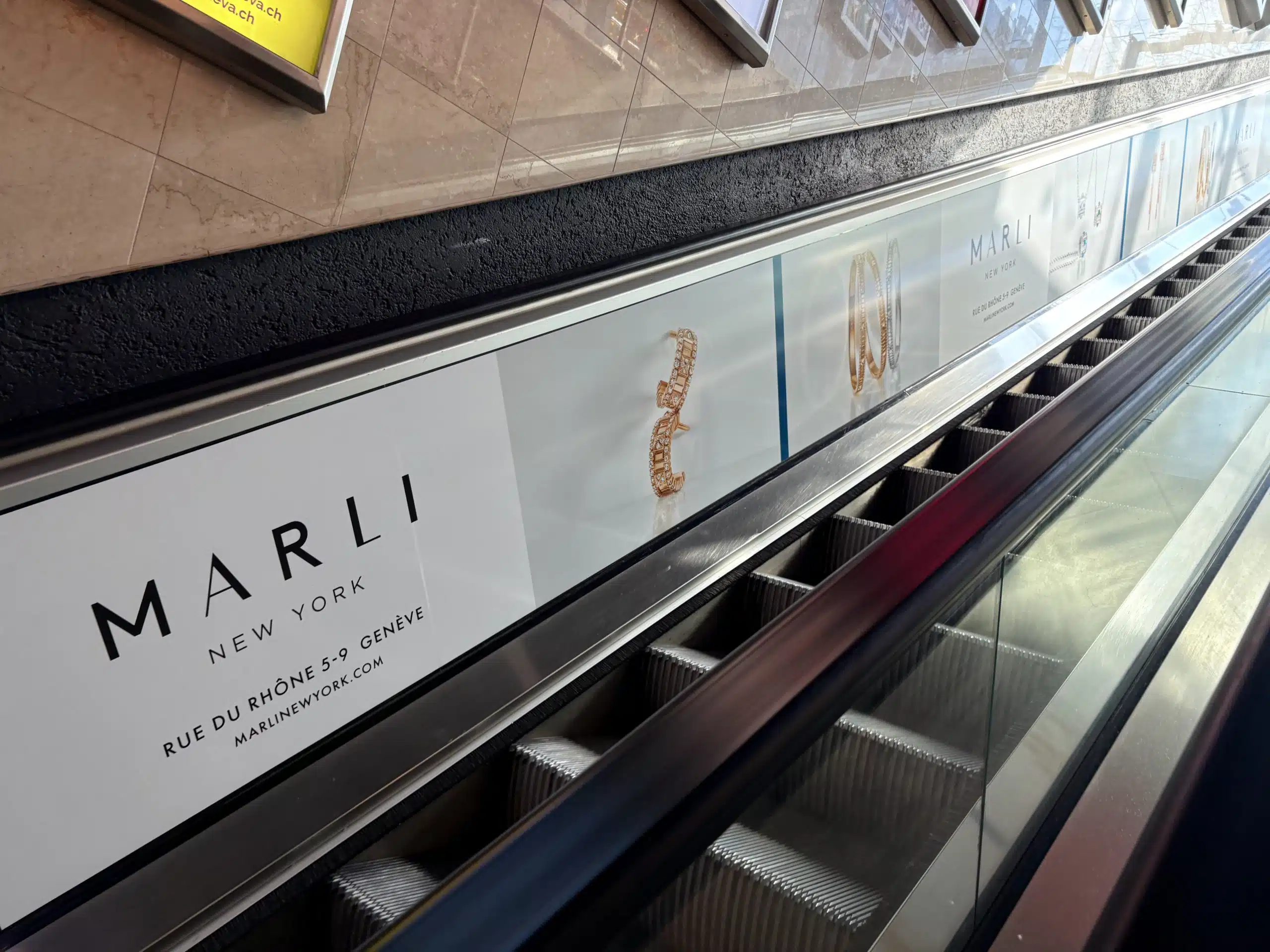Habillage publicitaire complet des escalators au parking du Mont-Blanc à Genève, utilisé pour une campagne immersive de la marque de joaillerie Marli New York.