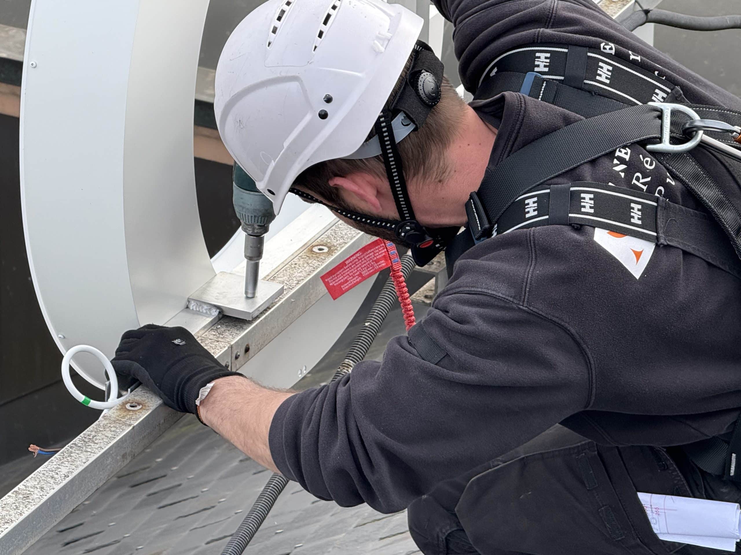Technicien installant une enseigne lumineuse connectée sur un bâtiment à Genève, garantissant une pose professionnelle et sécurisée