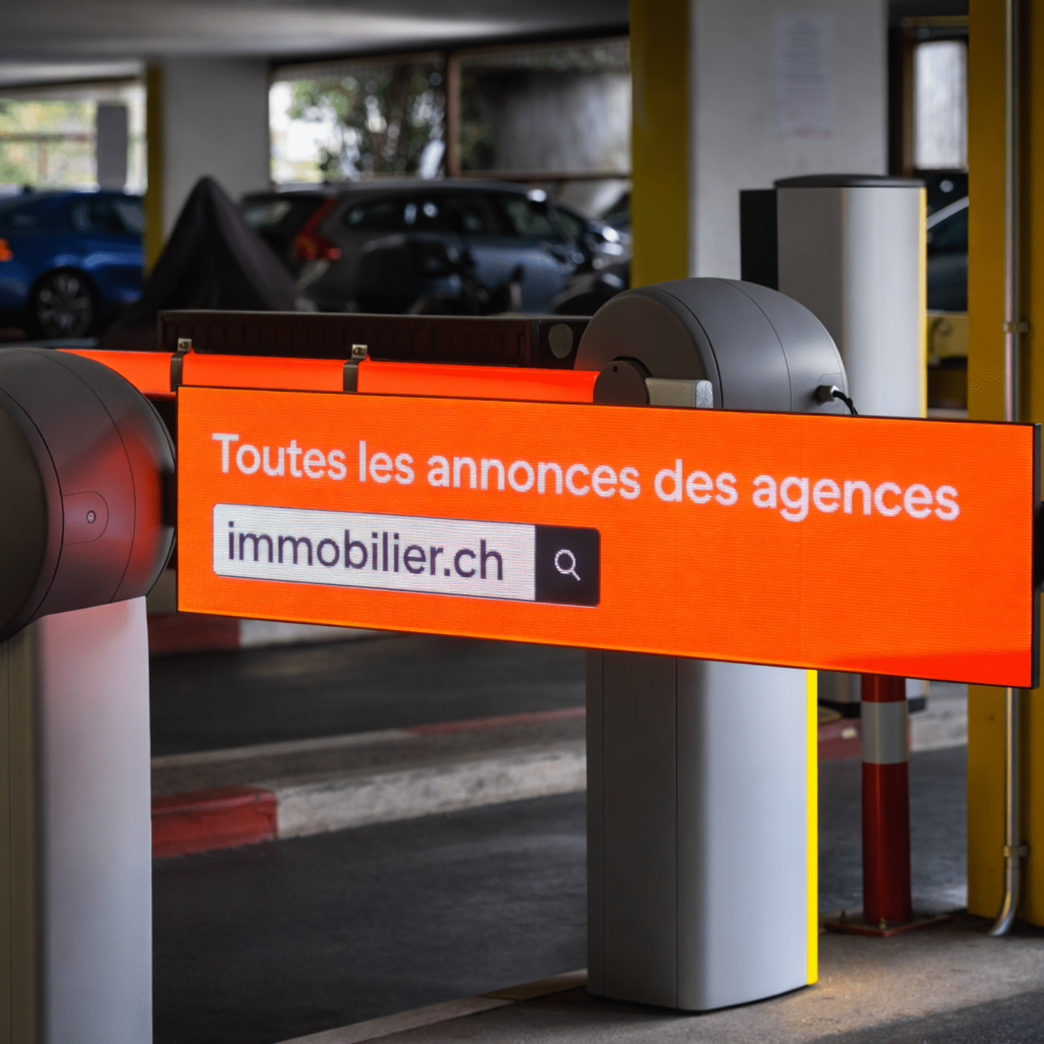 Barrières publicitaires LED du parking de Bellefontaine à Lausanne, diffusant la communication d’immobilier.ch à l’entrée du parking, visibles par les automobilistes dans un environnement couvert.