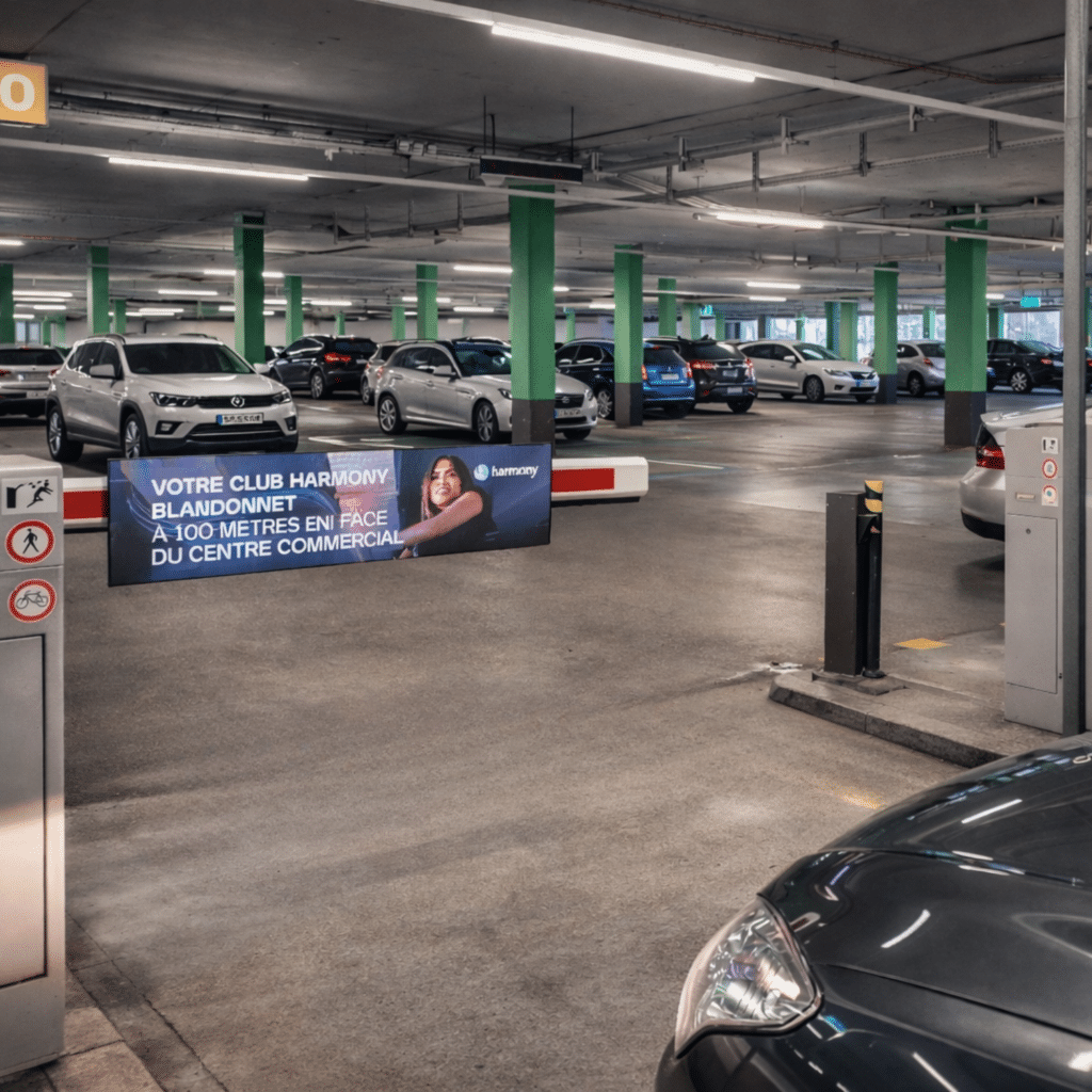 Spot publicitaire Black Friday Harmony Fitness sur les barrières digitales publicitaires du parking du centre commercial Blandonnet à Vernier, canton de Genève