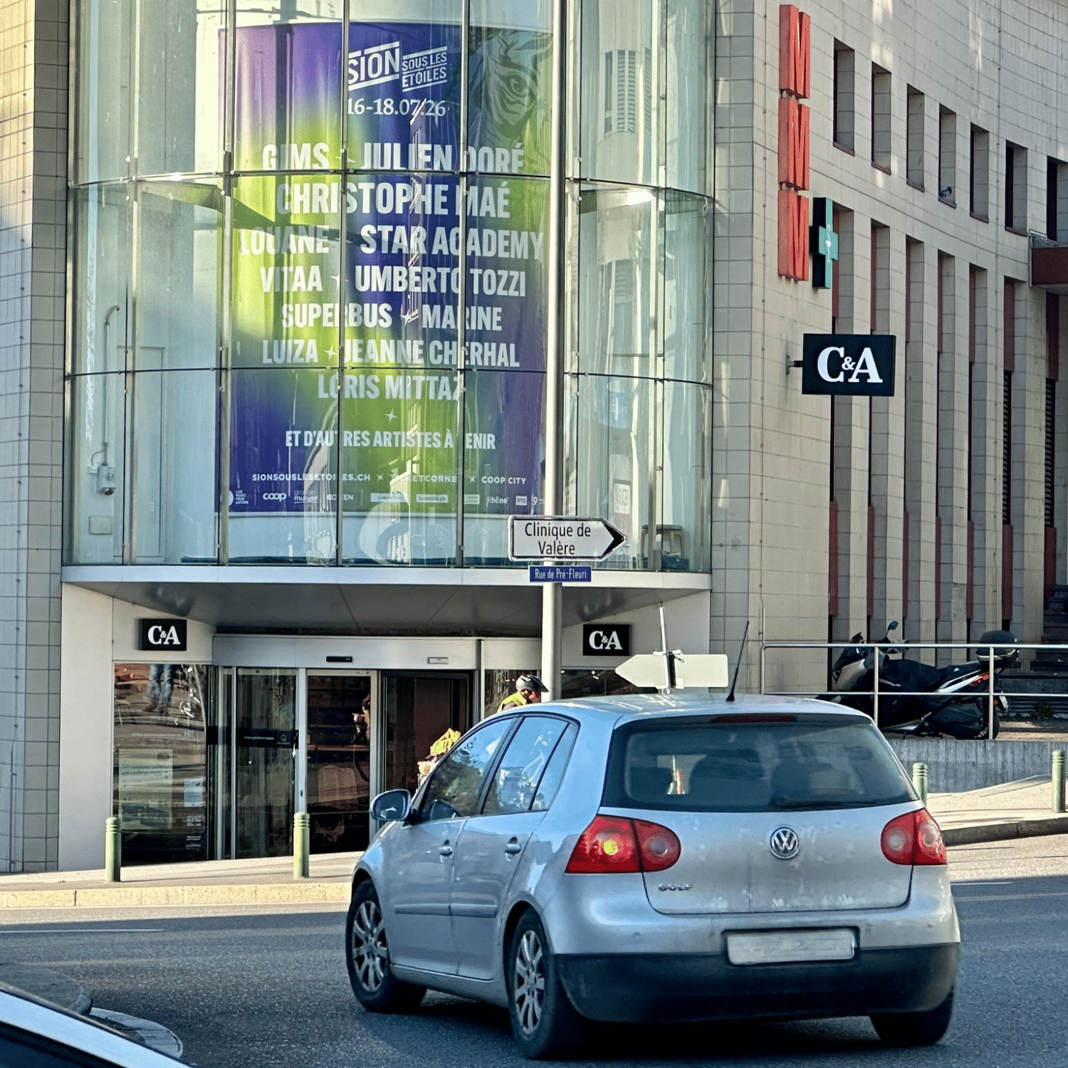 Mégaposter publicitaire rétroéclairé installé sur la façade du C&A à Sion, face au giratoire principal, mettant en avant l’événement Sion sous les étoiles produit par Live Music Production.